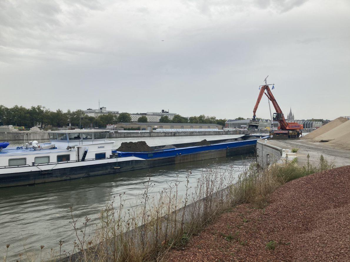 Une pelleteuse charge une péniche de terres excavées du chantier Métro 3 de la gare du Nord